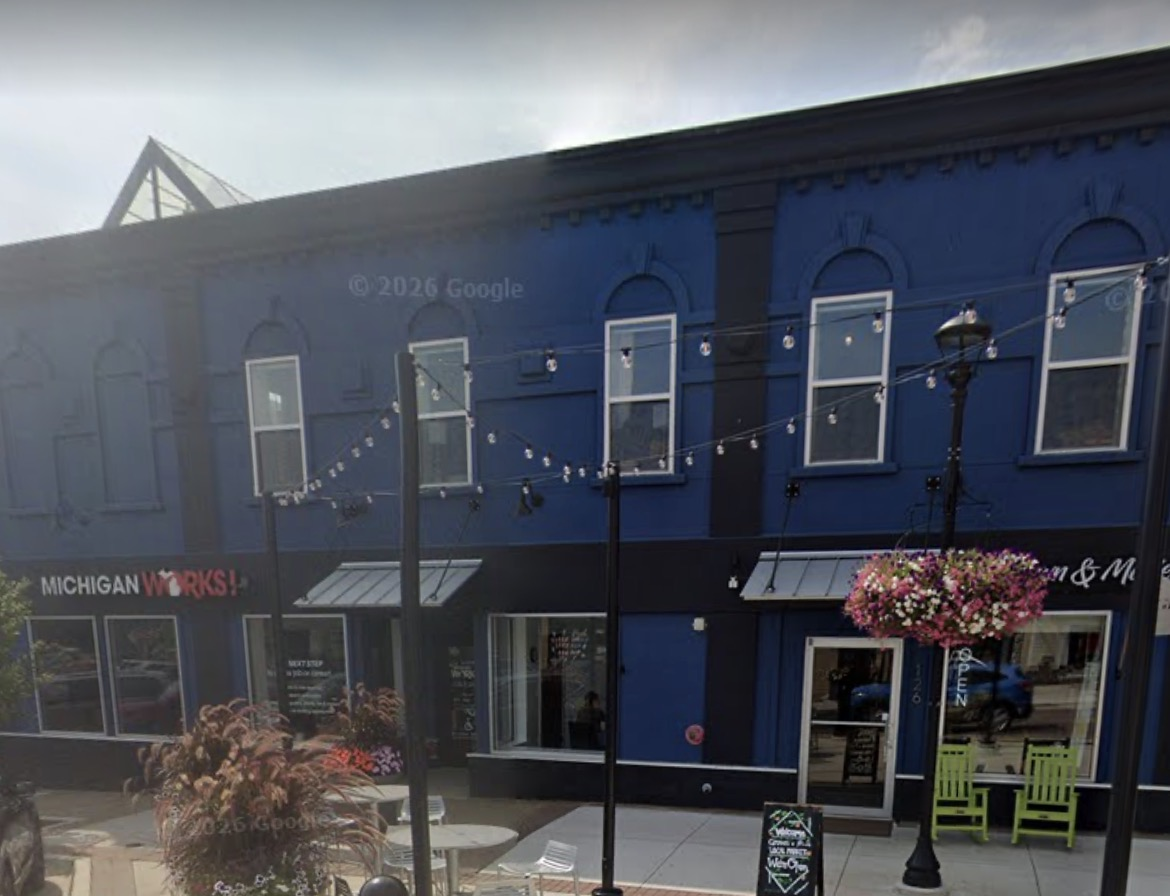 The Grown & Made Local Market blue storefront next to the neighboring building, with the outdoor patio on State Street in downtown Hastings, Michigan